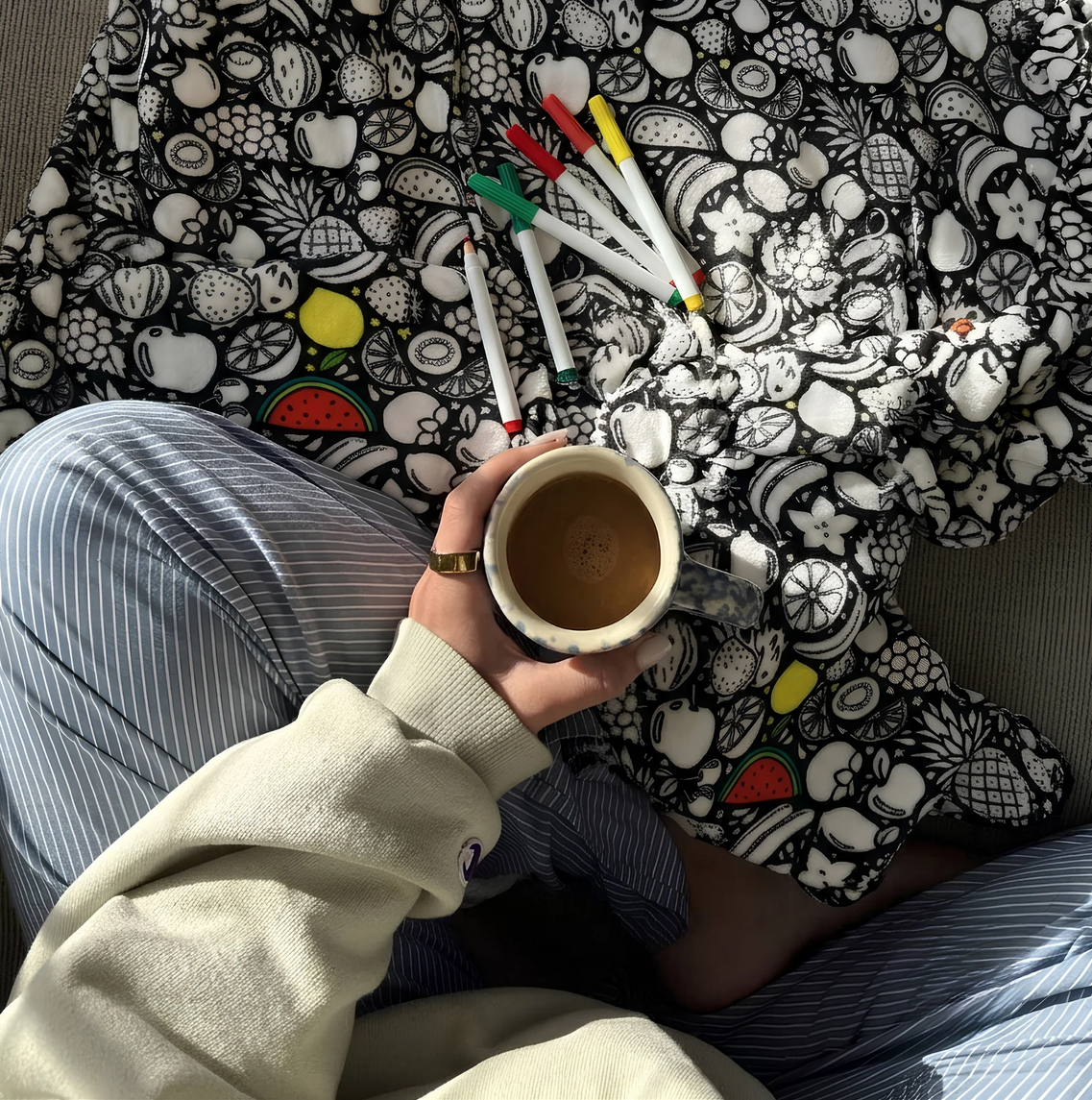 Manta Kolora en el sofá con marcadores de colores y una taza de café